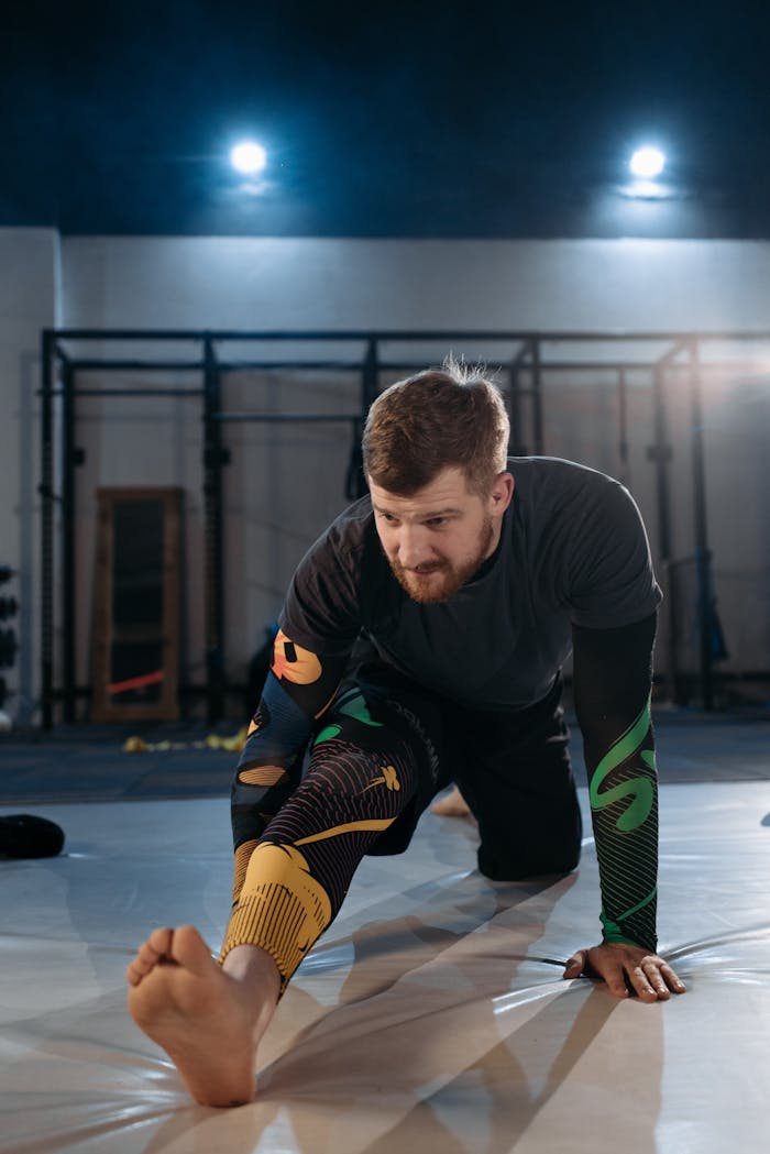 digital-01 Focused MMA fighter stretches on the gym mat during training session.
