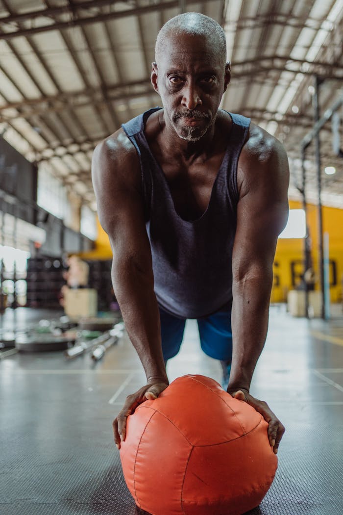 Services-02 Senior adult performing push up exercise with medicine ball in gym setting.