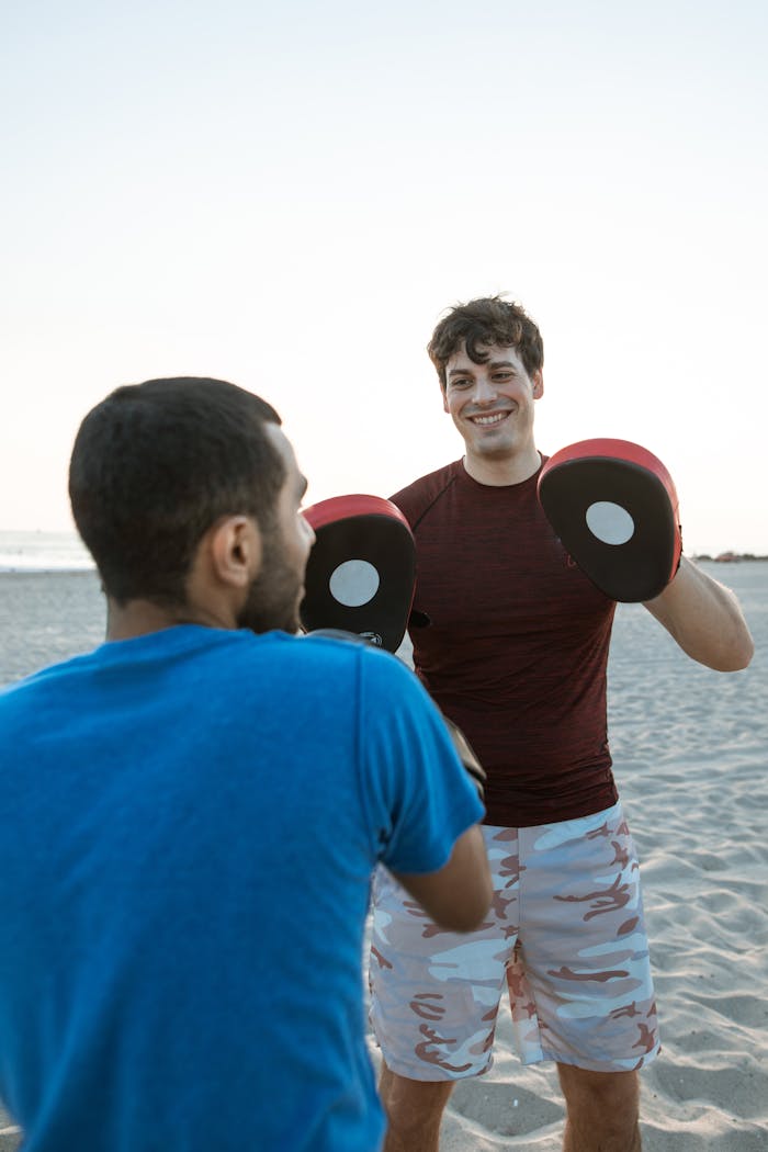 creative Two men training boxing on the beach at sunset, focusing on fitness and teamwork.